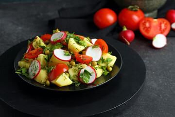 Plate of tasty Potato Salad with vegetables on dark background