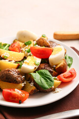 Plate of tasty potato salad with eggs and tomatoes on table, closeup