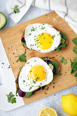 Delicious sandwiches with fried eggs on light background
