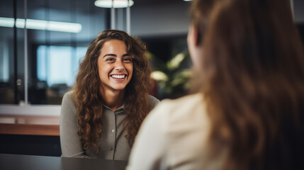 genuine smile and engagement of a young businesswoman as she listens to her partner in a coworking space - obrazy, fototapety, plakaty