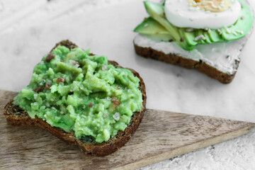 Board of tasty avocado toasts on light background