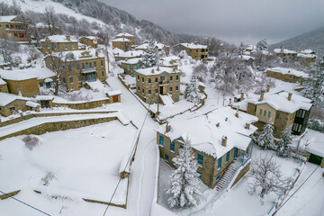 Aerial view of traditional architecture  with  stone buildings covered  with snow  during  winter season in the picturesque village of Nymfaio  Florinas, Greece