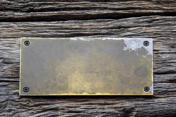 Antique blank brass rectangular plaque screwed with rusty screws to an old weathered board with...