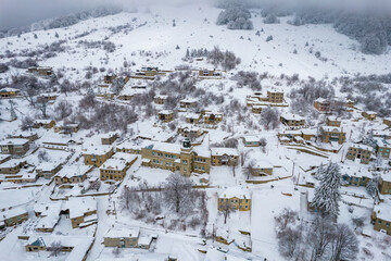 Aerial view of traditional architecture  with  stone buildings covered  with snow  during  winter season in the picturesque village of Nymfaio  Florinas, Greece