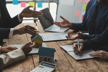 Entrepreneurs, business owners, accountants and real estate agents meet, discuss and use calculators to calculate budgets for purchasing a home project and calculate financial risks for clients.