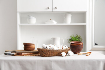Fototapeta na wymiar Basket of cotton flowers with kitchen dishes on table