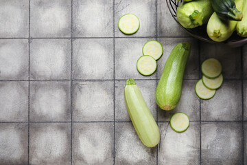 Fresh cut and whole zucchini on black tile background