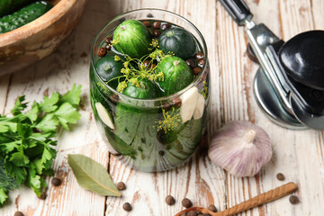 Jar with fresh cucumbers for preservation on light wooden background