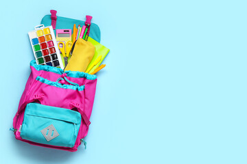 Stylish school backpack with different stationery on blue background