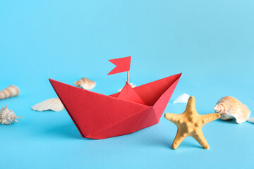 Red origami boat with seashells and starfish on blue background