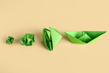 Green origami boat, flower and crumpled paper on light green background