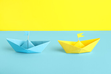 Colorful origami boats with flags on color background