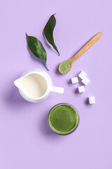 Composition with cup of fresh matcha tea, milk and sugar on lilac background