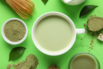 Composition with cup of fresh matcha tea, powder and chasen on green background, closeup