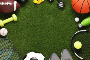 Frame of different sport tools on green grass, flat lay. Space for text - obrazy, fototapety, plakaty