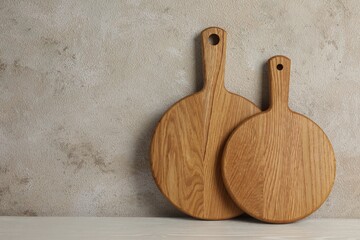 Wooden cutting boards on white table near textured wall, space for text