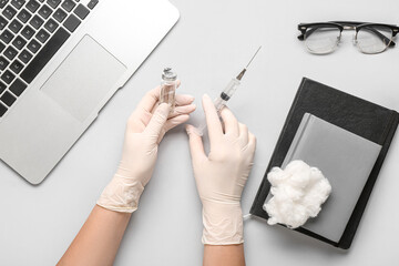 Doctor with vaccine and syringe on light background, top view