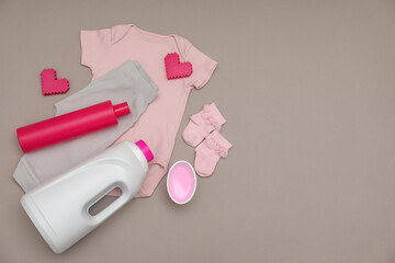 Bottles of laundry detergents, baby clothes and decorative hearts on grey background, flat lay....