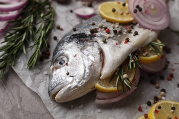 Fresh raw dorado fish with spices, lemon and onion on table, closeup