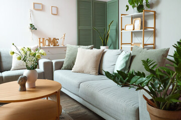 Interior of modern living room with grey sofa and flower vase on coffee table