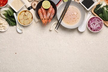 Cooking delicious ramen soup. Different ingredients on beige table, flat lay. Space for text