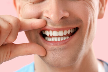 Male dentist smiling on pink background, closeup