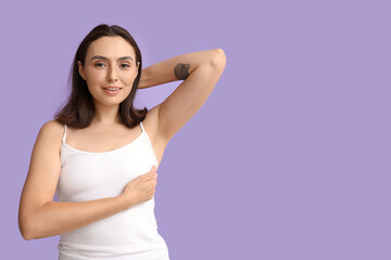 Obraz premium Young woman checking her breast on lilac background. Cancer awareness concept