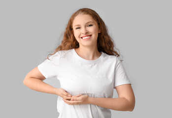 Young woman checking her breast on light background. Cancer awareness concept