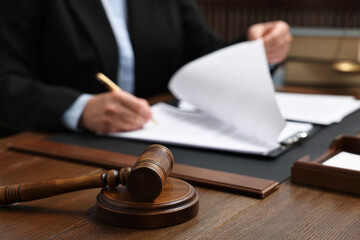 Lawyer working with documents at wooden table indoors, focus on gavel