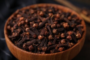 Aromatic cloves in bowl on table, closeup