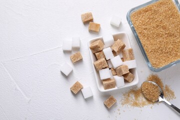 Bowls and spoon with different types of sugar on white table, flat lay. Space for text
