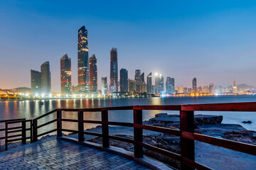 Fototapeta na wymiar Night view of high-rise buildings and seaside pedestrian walkways in Fushan Bay, Qingdao, Shandong, China