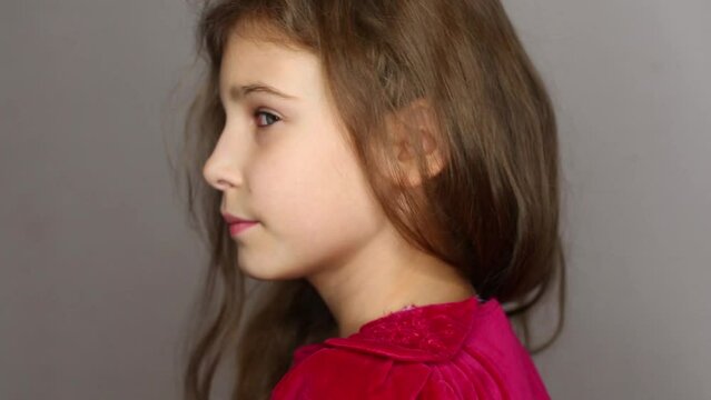 Portrait of cute little girl in red dress turning head in studio