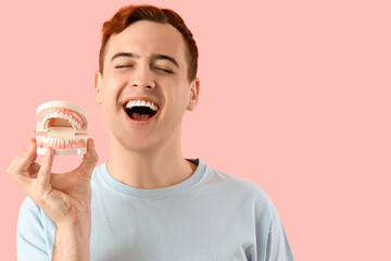 Young man with jaw model on pink background, closeup