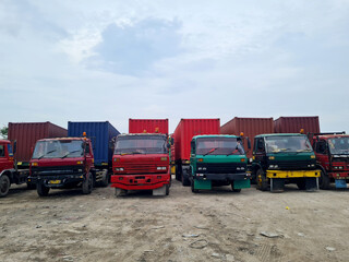 rows of trailer trucks carrying containers parked in a row at the container depot or container yard at the port.