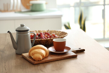 Kitchen table with grapes, cup of tea and croissant in modern kitchen, closeup