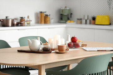 Fototapeta na wymiar Wooden table with coffee, apples and burning candles in modern kitchen