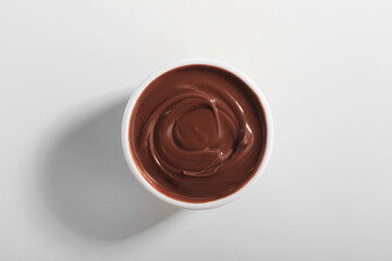 Bowl of tasty melted chocolate on white background
