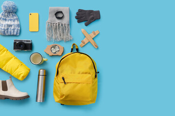 Winter accessories with backpack on blue background, top view
