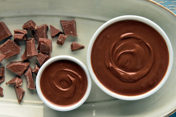 Bowls of tasty melted chocolate on plate, closeup