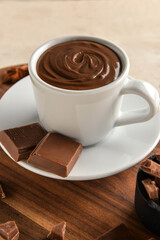 Cup with tasty melted chocolate on white wooden background