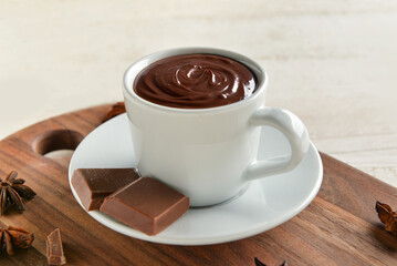 Cup with tasty melted chocolate on white wooden background