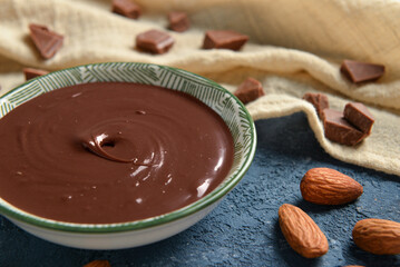 Bowl of tasty melted chocolate on blue background