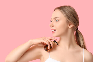 Beautiful young woman with bottle of cosmetic product on pink background