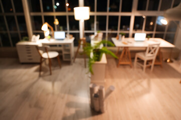 Blurred view of office with desks and glowing lamps at night