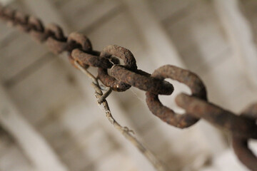 Beautiful composition with a selective focus on a rusted iron chain in a barn. Diagonal and oblique...