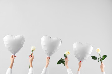 Female hands holding heart-shaped balloons and beautiful roses on white background. Valentine's Day...