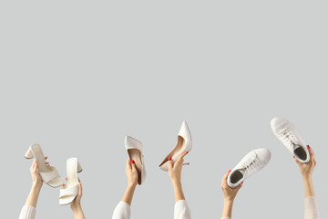 Female hands holding shoes on grey background