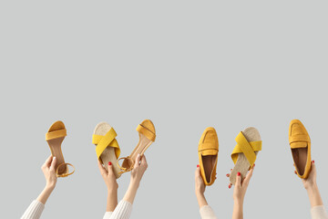 Female hands holding sandals on grey background