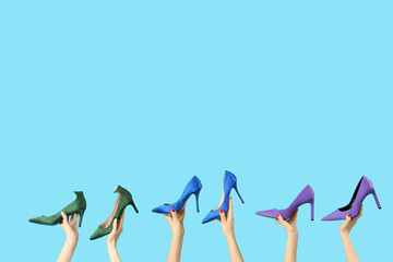 Female hands holding different shoes on blue background